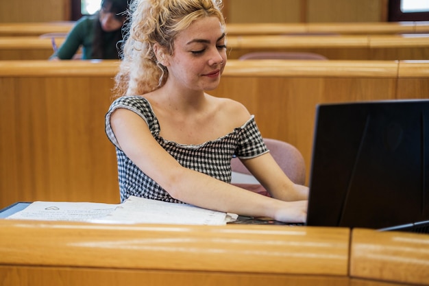 Młoda kobieta robi notatki na laptopie podczas zajęć na uniwersytecie Concept studiuje przygotowanie do edukacji
