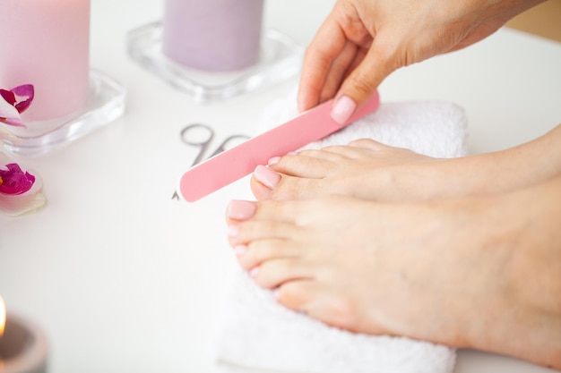 Młoda kobieta robi profesjonalny pedicure w domu