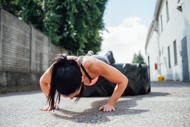 Zdjęcie młoda kobieta robi push up szkolenia odkryty przy użyciu gigantyczne opony