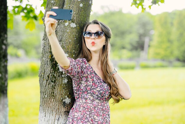 Młoda kobieta robi selfie z telefonem w parku