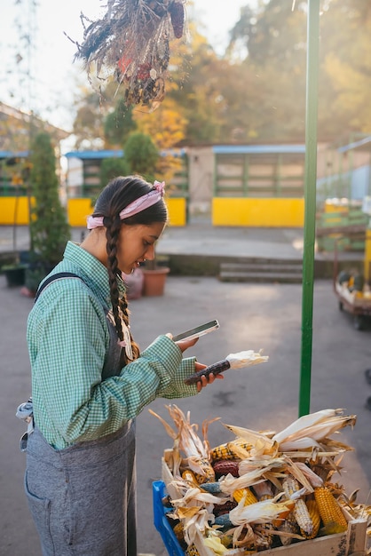 Młoda kobieta robi zdjęcie kolby kukurydzy na targu