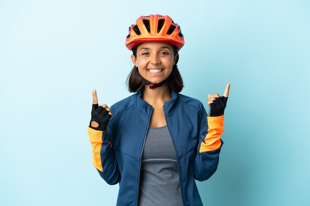 Młoda kobieta rowerzysta na białym tle na niebieskim tle, wskazując na świetny pomysł