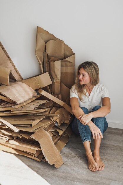 Młoda kobieta różdżka stos odpadów kartonowych w domu Koncepcje recyklingu papieru i sortowania odpadów