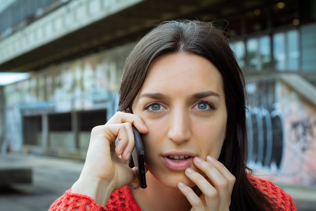 Młoda kobieta rozmawia na jej telefon komórkowy.