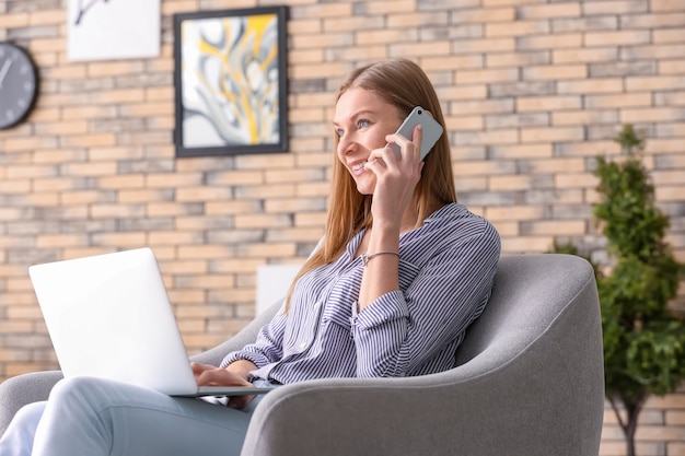 Młoda Kobieta Rozmawia Przez Telefon Podczas Pracy Na Laptopie W Domu