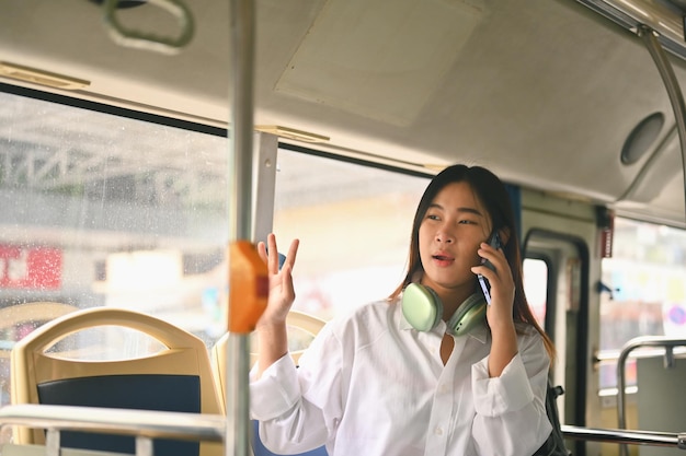 Młoda kobieta rozmawiająca przez telefon komórkowy podczas podróży autobusem Koncepcja życia miejskiego i transportu