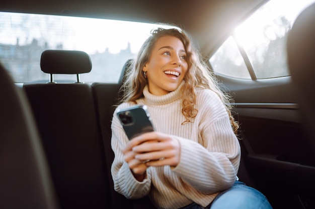 Młoda kobieta rozmawiająca przez telefon na tylnym siedzeniu samochodu Koncepcja blogowania o technologii biznesowej