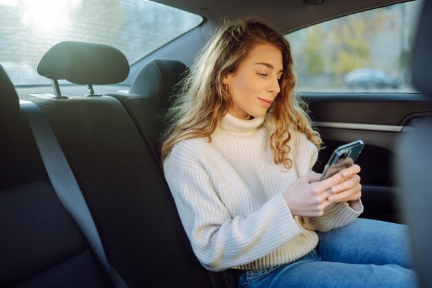Młoda kobieta rozmawiająca przez telefon na tylnym siedzeniu samochodu Koncepcja blogowania technologii biznesowej