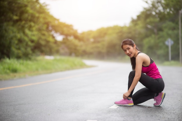 młoda kobieta runner wiązanie sznurowadło na drodze