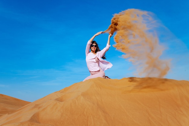 Młoda kobieta rzucająca piaskiem na pustynię orande
