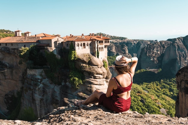 Młoda kobieta siada z powrotem do aparatu na szczycie góry i patrzy na dolinę i skały Koncepcja podróżowania szczęście wolność Podróżnik cieszący się krajobrazem z góry Meteory Grecja