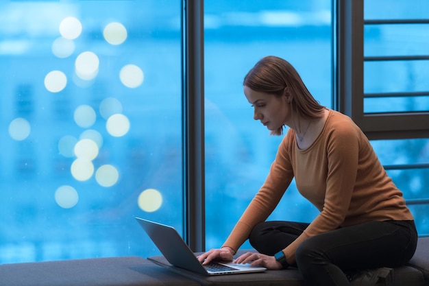Młoda kobieta siedząca w nowoczesnej przestrzeni podczas pracy nad projektem na laptopie selektywne focus