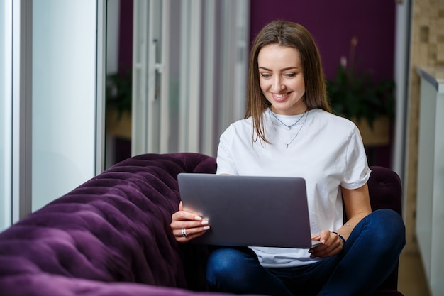 Młoda Kobieta Siedzi Na Kanapie I Pracuje Na Laptopie Zdalnie Z Pracy