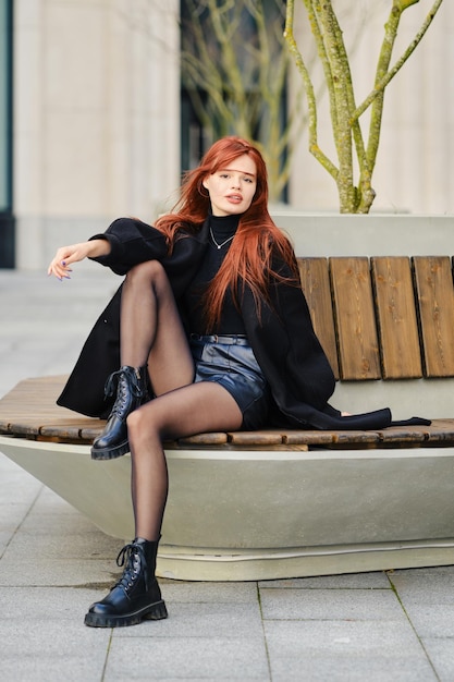 Młoda kobieta siedzi na ławce na ulicy