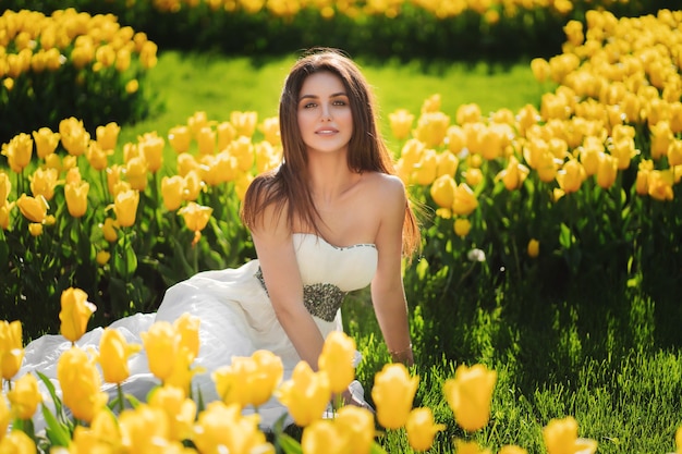 Młoda kobieta siedzi na polu żółtych tulipanów