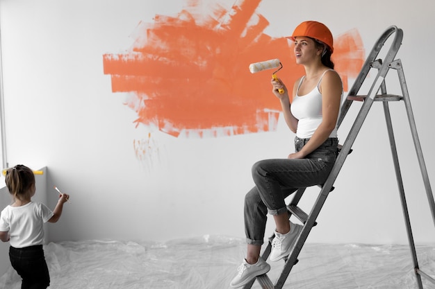 Młoda kobieta siedzi na schodach pomarańczowy kask na głowie. Koncepcja remontu domu.