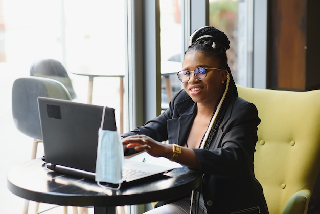 Młoda kobieta siedzi w kawiarni pracuje na laptopie