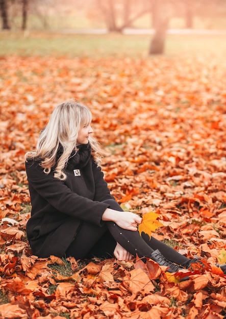 Młoda kobieta siedzi w publicznym parku jesienią