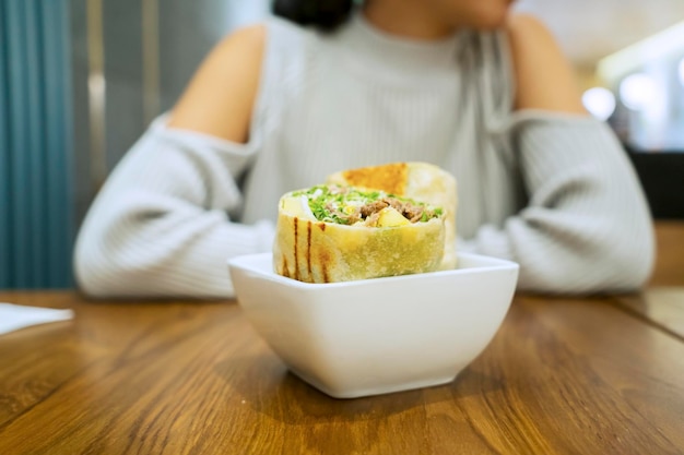 Młoda kobieta siedzi z burrito w restauracji