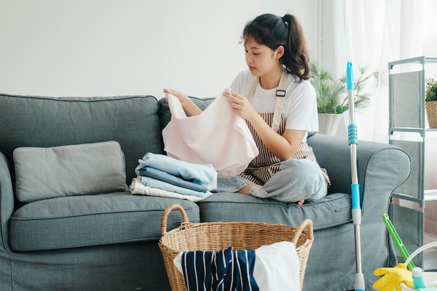 Młoda kobieta składane ubrania na kanapie w domu