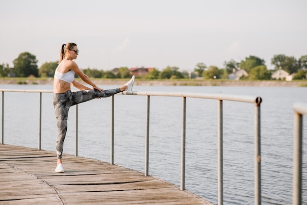 Młoda kobieta slim fit robi ćwiczenia sportowe na świeżym powietrzu w parku w słoneczny dzień