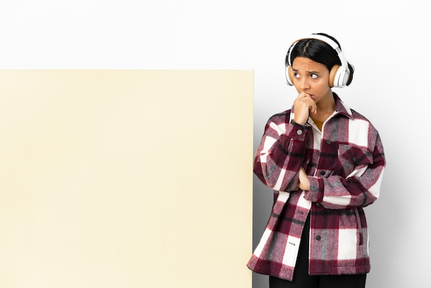 Młoda kobieta słucha muzyki z dużym pustym plakietką na białym tle, mając wątpliwości iz niejasnym wyrazem twarzy