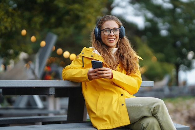 Młoda kobieta słucha podcastu muzycznego na zewnątrz Komunikacja w sieciach społecznościowych Styl życia