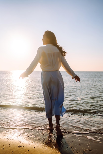 Młoda kobieta spaceru w zachód słońca na plaży Czas letni Koncepcja stylu życia weekend podróży