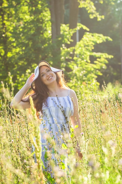 Zdjęcie młoda kobieta spaceru wśród kwiatów w słoneczny letni dzień. koncepcja radości obcowania z letnią naturą