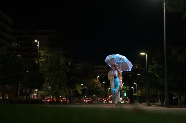 Młoda kobieta spaceru z parasolem ze światłami w nocy