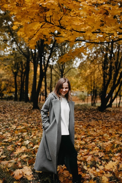 Młoda Kobieta Spacerująca Po Jesiennym Parku W Długim Płaszczu