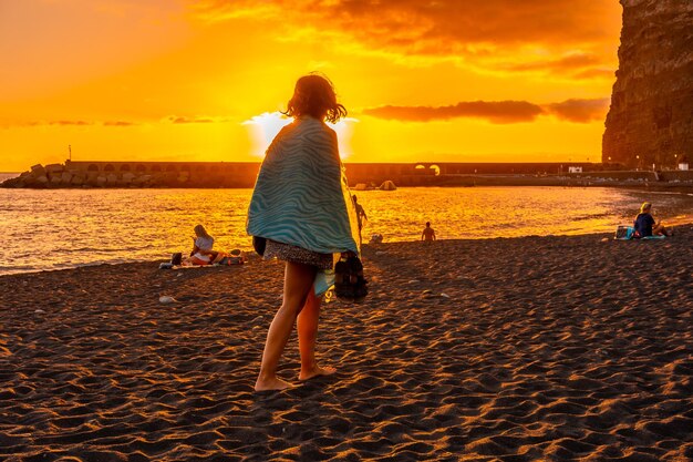 Młoda kobieta spacerująca po plaży o zachodzie słońca w Puerto de Tazacorte