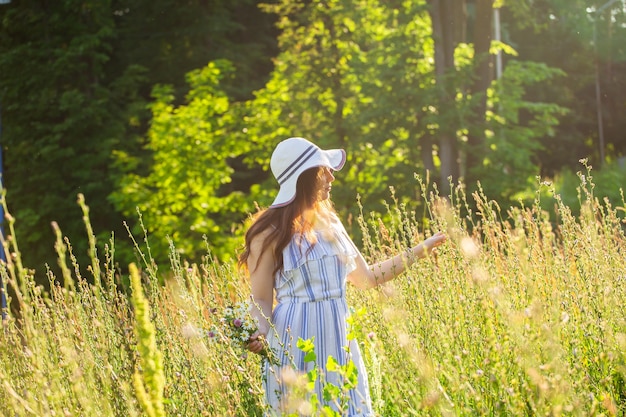 Młoda kobieta spacerująca wśród polnych kwiatów w słoneczny letni dzień koncepcja radości z komunikowania się
