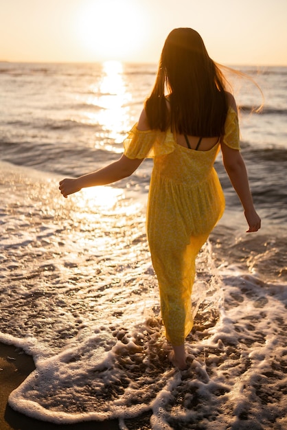 Młoda kobieta spaceruje brzegiem morza o zachodzie słońca Natura relaksuje koncepcję stylu życia