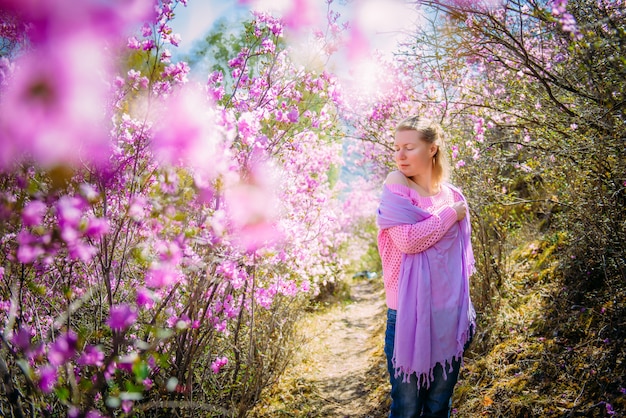 Młoda Kobieta Stoi, Odpoczywa I Cieszy Się Wiosennego Kwitnienia Ogród Wśród Rododendronowych Kwiatów W świetle Słonecznym. życie Na Wsi.