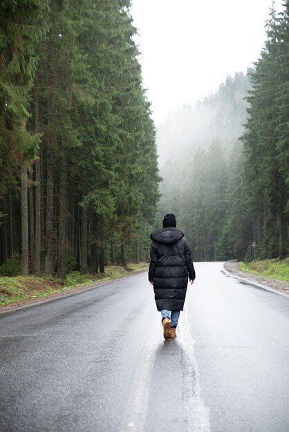 Młoda kobieta stojąca na środku drogi w zimowym lesie w górach