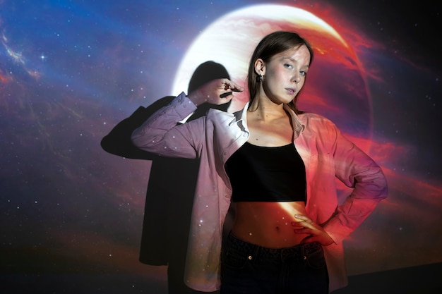 Zdjęcie młoda kobieta stojąca w projekcji tekstury wszechświata