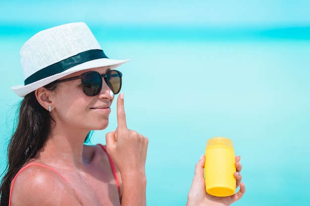 Młoda kobieta stosuje śmietankę na jej nosie przy plażą