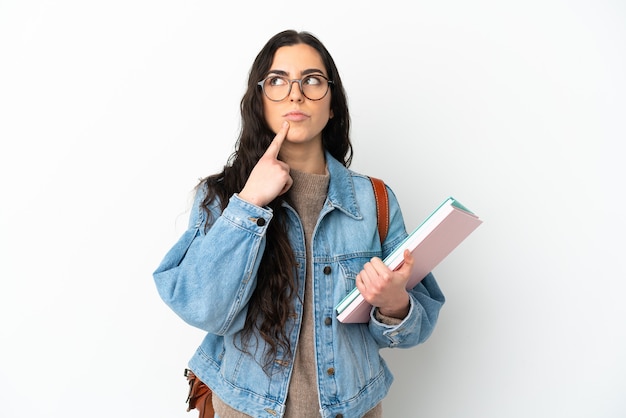 Młoda kobieta student na białym tle na białym tle, mając wątpliwości, patrząc w górę