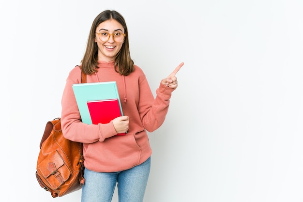 Młoda kobieta student uśmiecha się i wskazuje na bok, pokazując coś