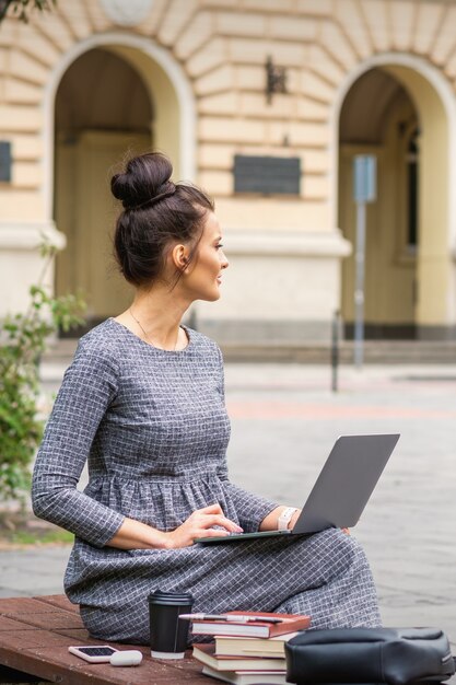 Młoda Kobieta Student Używa Laptopa Na ławce Na Ulicy W Pobliżu Uniwersytetu