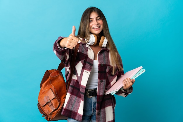 Młoda kobieta studentka odizolowana na niebiesko z kciukami do góry, ponieważ stało się coś dobrego