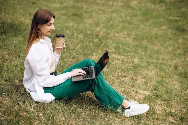 Młoda kobieta studentka pracuje na laptopie w parku