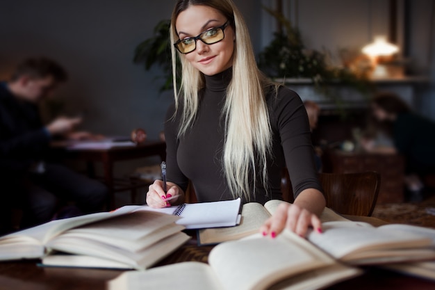 Młoda kobieta studentka uniwersytetu. Przygotowywanie egzaminów i lekcji nauki w bibliotece publicznej.