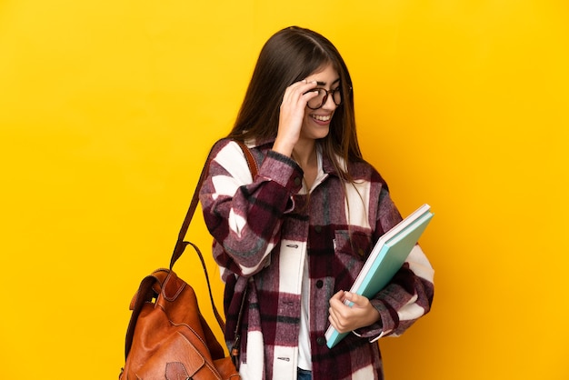 Młoda kobieta studentów na białym tle na żółtej ścianie, śmiejąc się