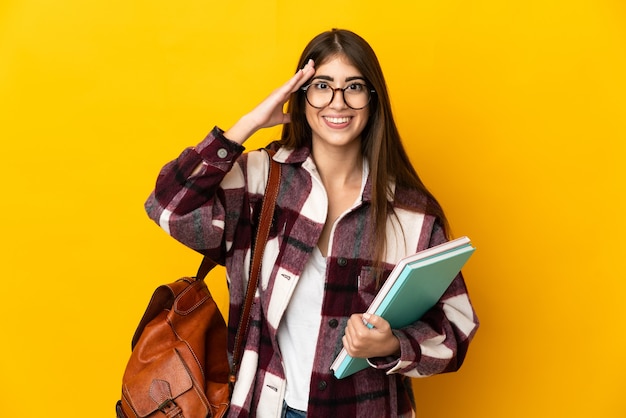 Młoda kobieta studentów na białym tle na żółtej ścianie z wyrazem zaskoczenia