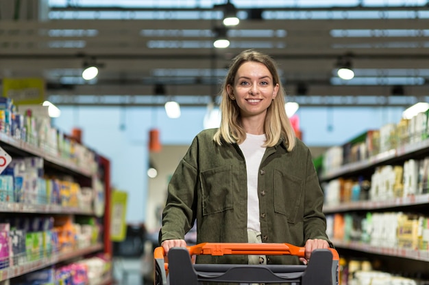 Młoda kobieta szczęśliwa pchanie wózka spędza czas w supermarkecie lub sklepie w centrum handlowym. Kobieta spacer z wózkiem. Codzienne zakupy i artykuły spożywcze Żywność na rynku. radosna Ładna kobieta w zwykłych ubraniach chodzenia