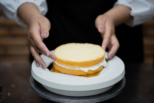 Młoda kobieta szefa kuchni kucharstwa tort w kuchni