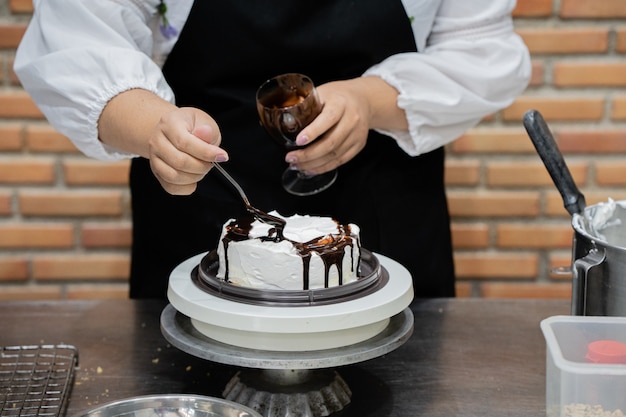 Zdjęcie młoda kobieta szefa kuchni kucharstwa tort w kuchni