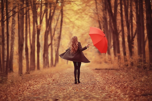 Młoda kobieta tańczy w jesiennym parku z parasolem